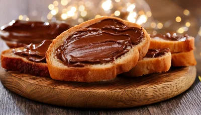 Slices Of Bread With Chocolate Spread On Wooden Board