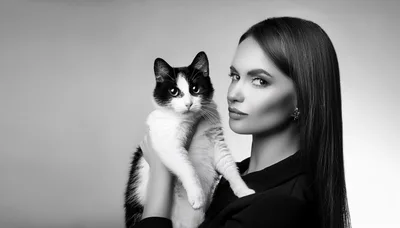 Elegant Woman Holding A Black And White Cat