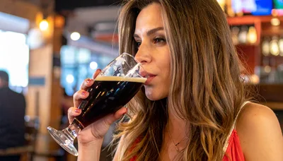 Woman Drinking Dark Beer In A Restaurant