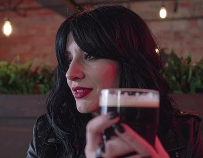 Woman With Dark Hair Holding A Pint Of Stout
