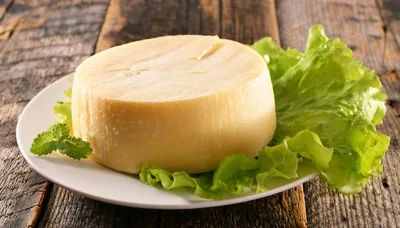 Round Wheel Of Cheese On A Plate With Lettuce