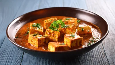 Bowl Of Paneer Butter Masala On Wooden Table