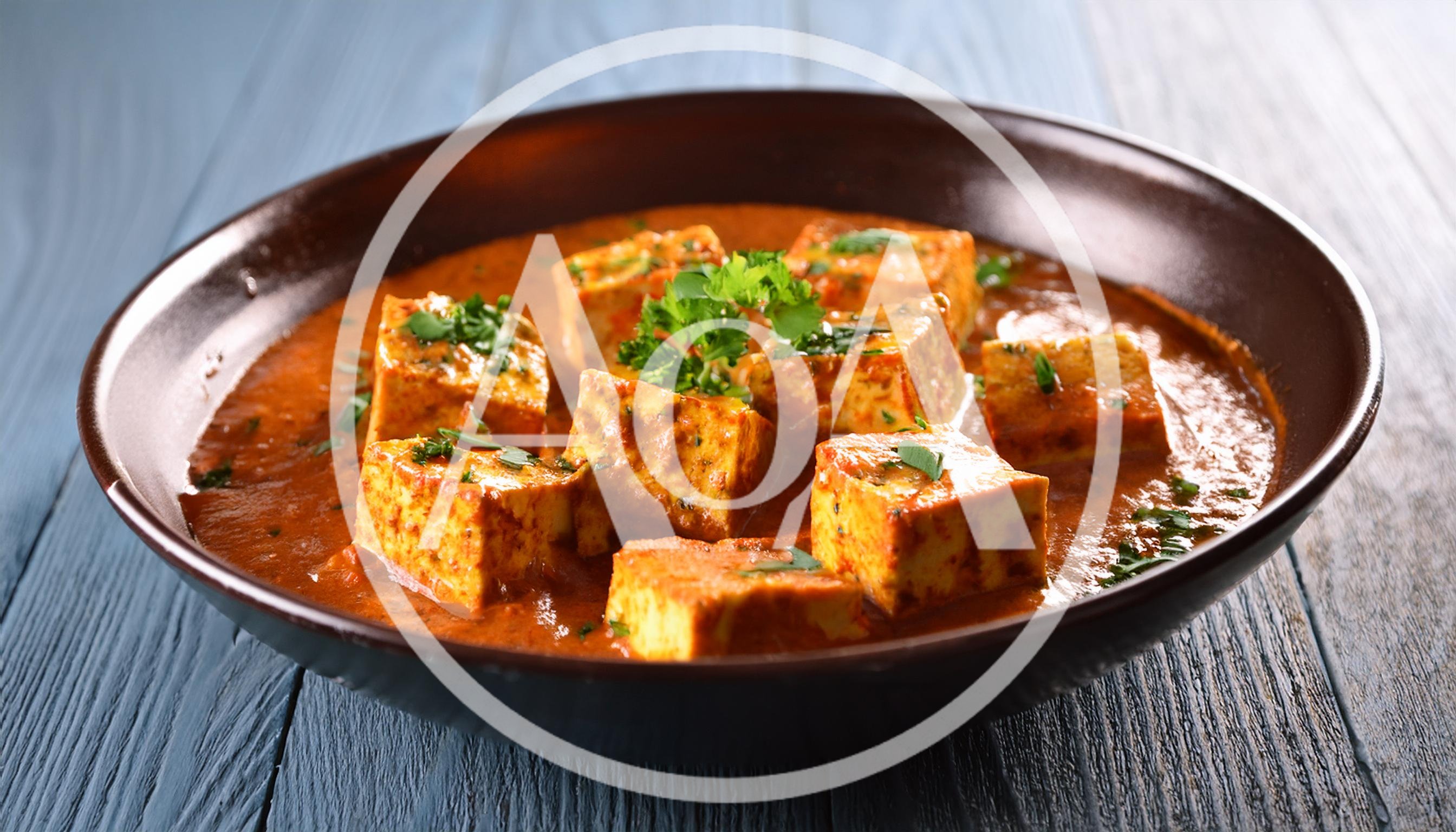 Bowl Of Paneer Butter Masala On Wooden Table