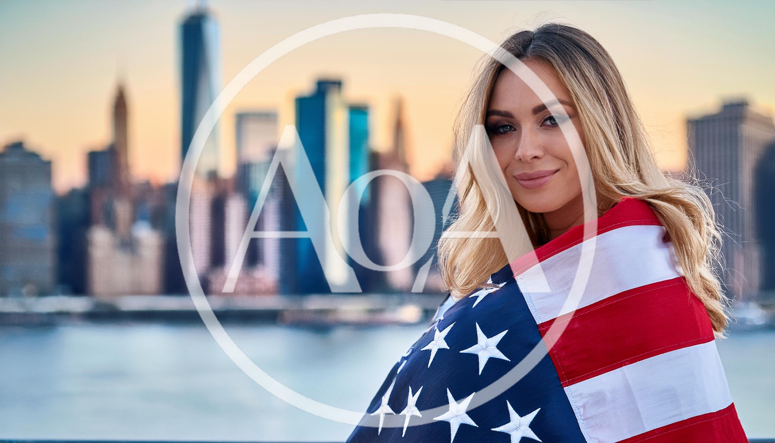 Blonde Woman Wrapped In American Flag Before City Skyline
