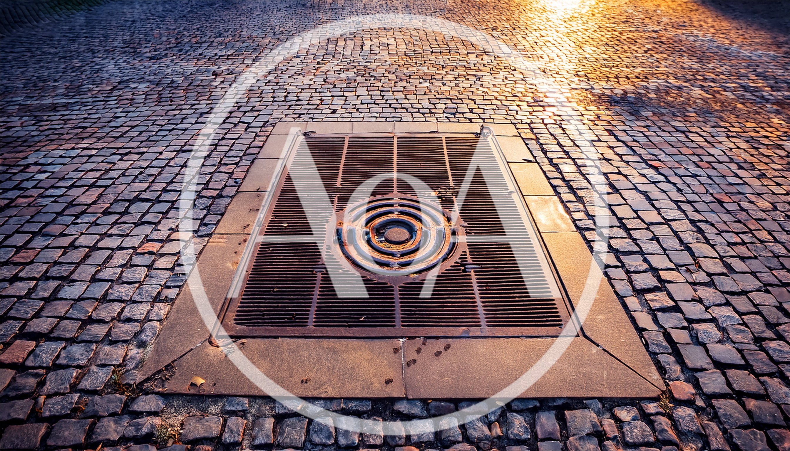 Rectangular Metal Storm Drain Grate On Cobblestone Street