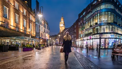 Woman Walking Down A Wet City Street At Twilight