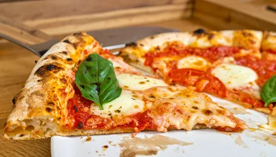 Freshly Baked Margherita Pizza Slice on Wooden Table