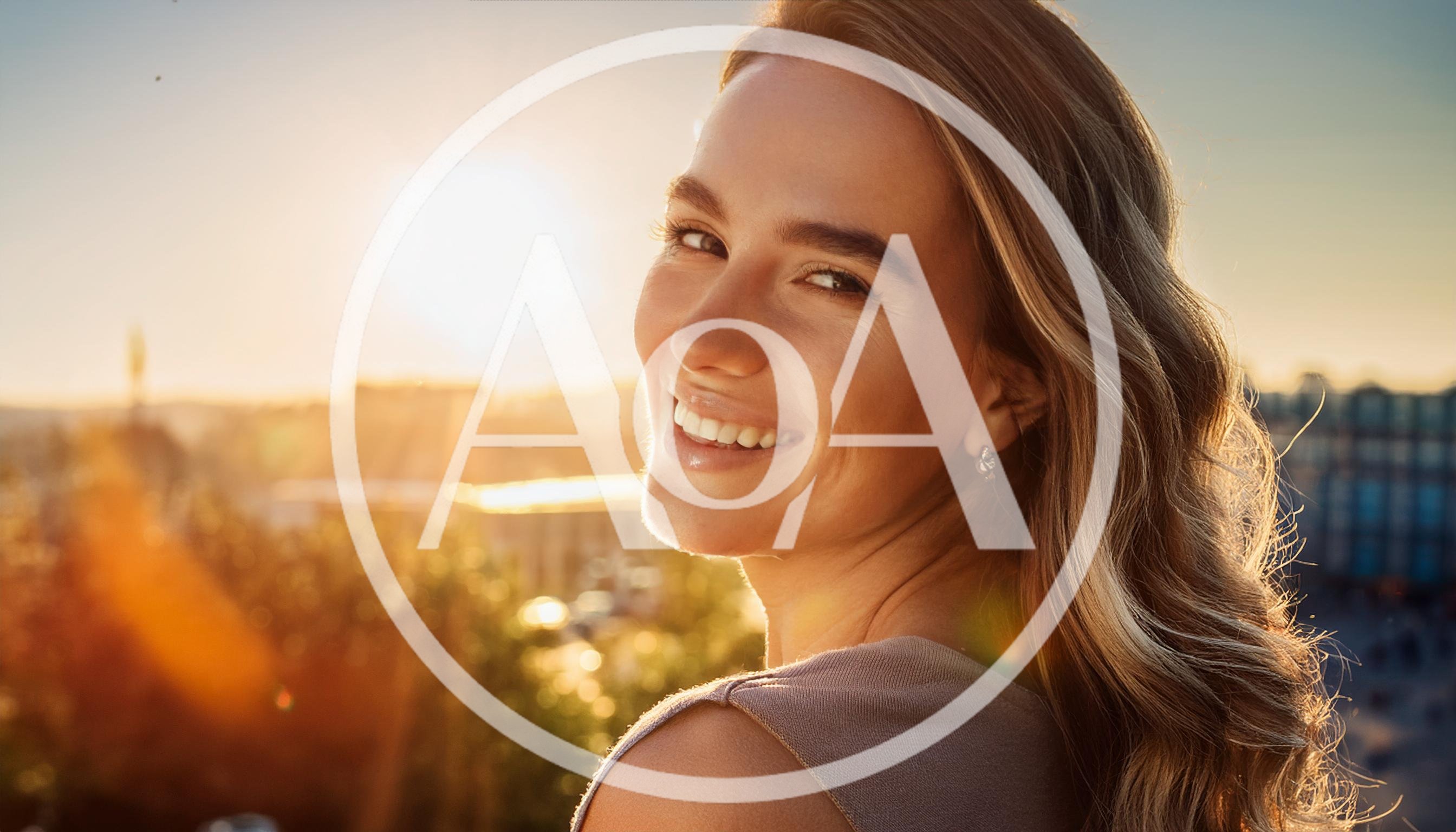 Smiling Young Woman Looking Back Over Shoulder At Sunset
