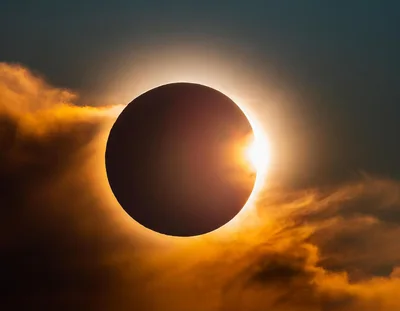 Solar Eclipse With Glowing Sun Corona And Clouds
