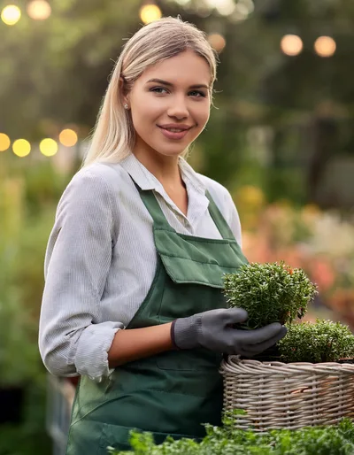 Young Female Gardener Holding Potted Plants In A Greenhouse