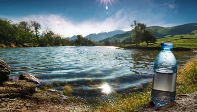 Plastic Water Bottle Sitting By A Scenic Mountain Lake