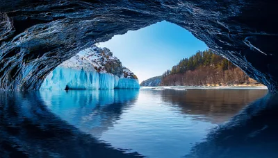 Ice Cave Opening Overlooking A Frozen Lake