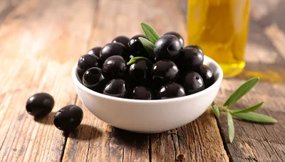 Black Olives in a White Bowl on Wooden Table