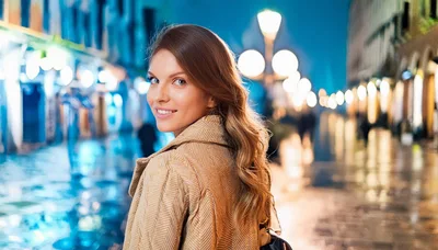 Young Woman Walking Through Illuminated City Street At Night