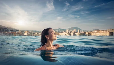 Young Woman Swimming In An Infinity Pool