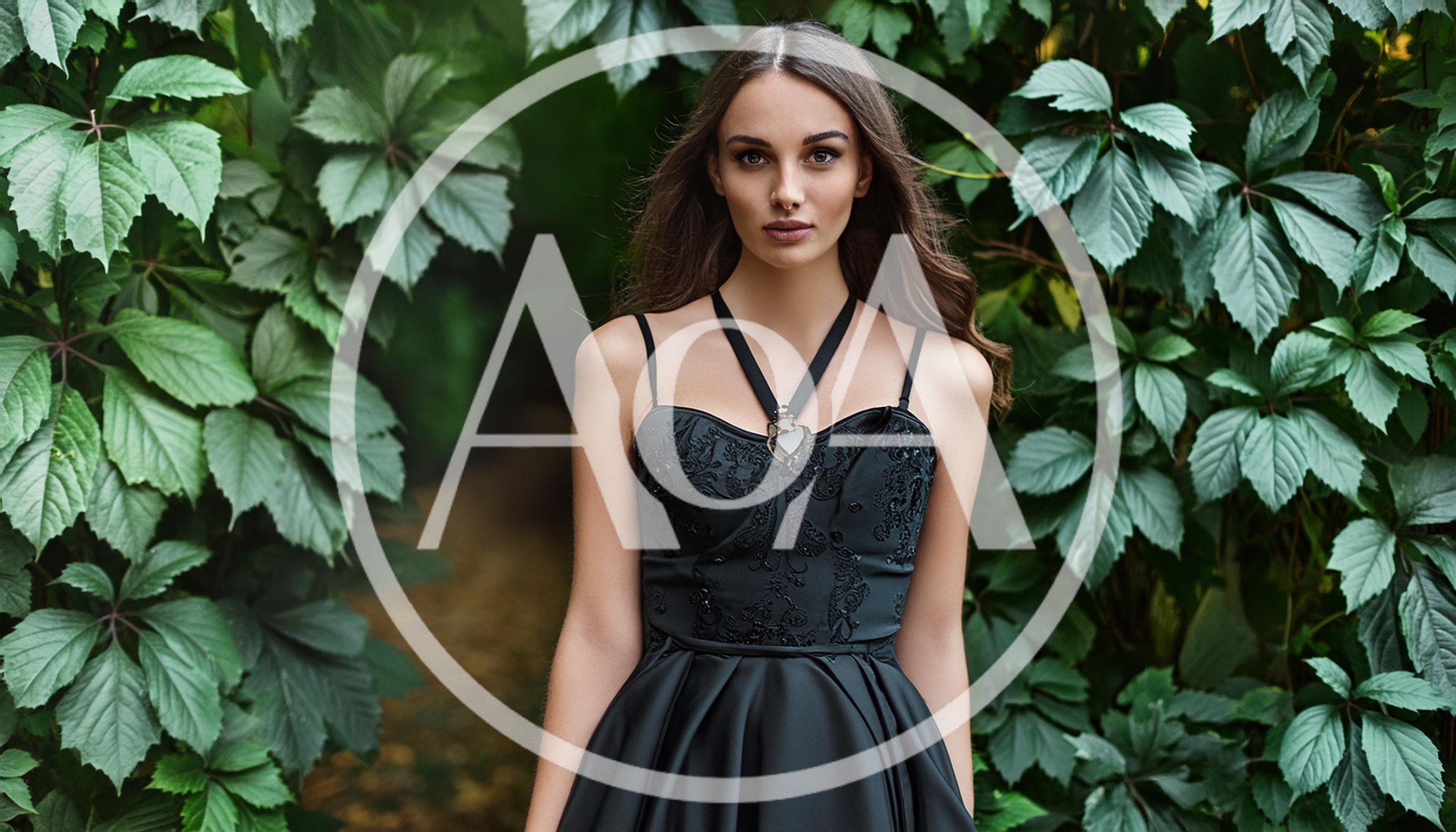 Young Woman In Black Dress Standing In Lush Foliage