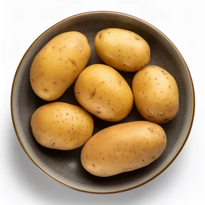 Six Raw Potatoes In A Dark Ceramic Bowl
