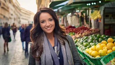 Smiling Woman Standing At An Outdoor Fruit Market