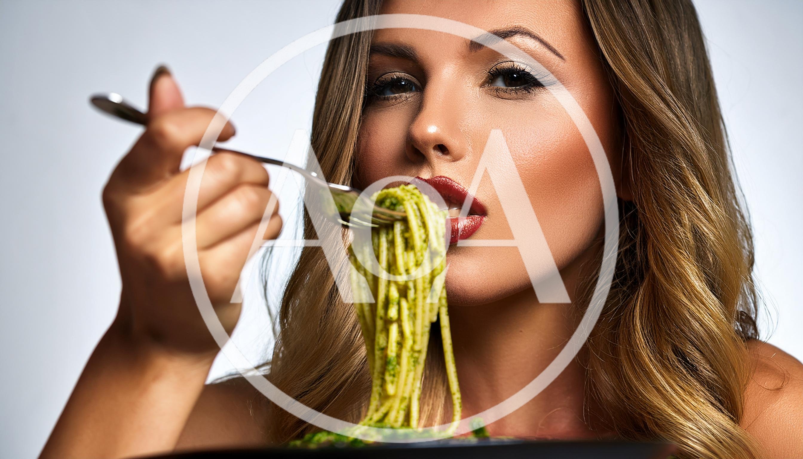 Beautiful Woman Eating Pesto Pasta With A Fork