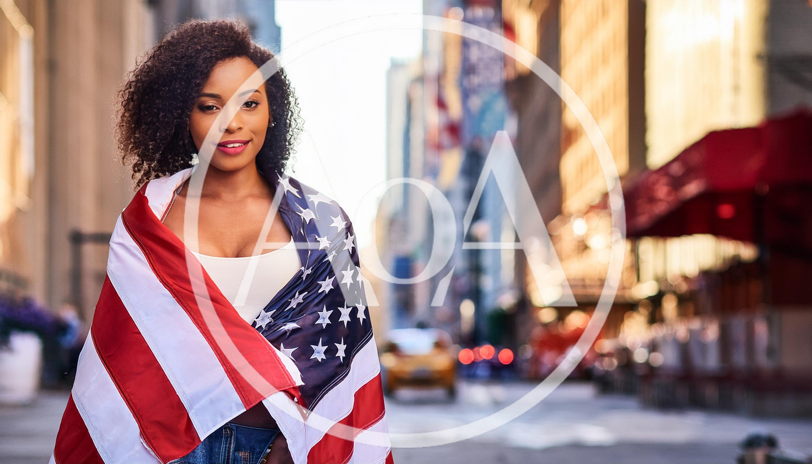 Young Woman Wrapped In American Flag On City Street