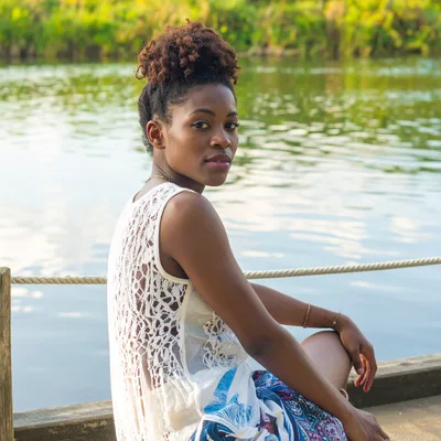 Young Woman Sitting On A Wooden Dock By The River