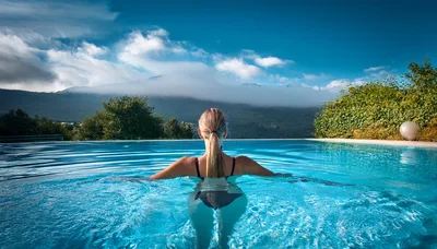 Woman Relaxing In Infinity Pool With Mountain View