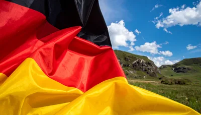 German Flag Waving Against A Mountain Landscape