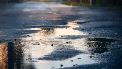 Rain Falling Into Puddles On Asphalt Road