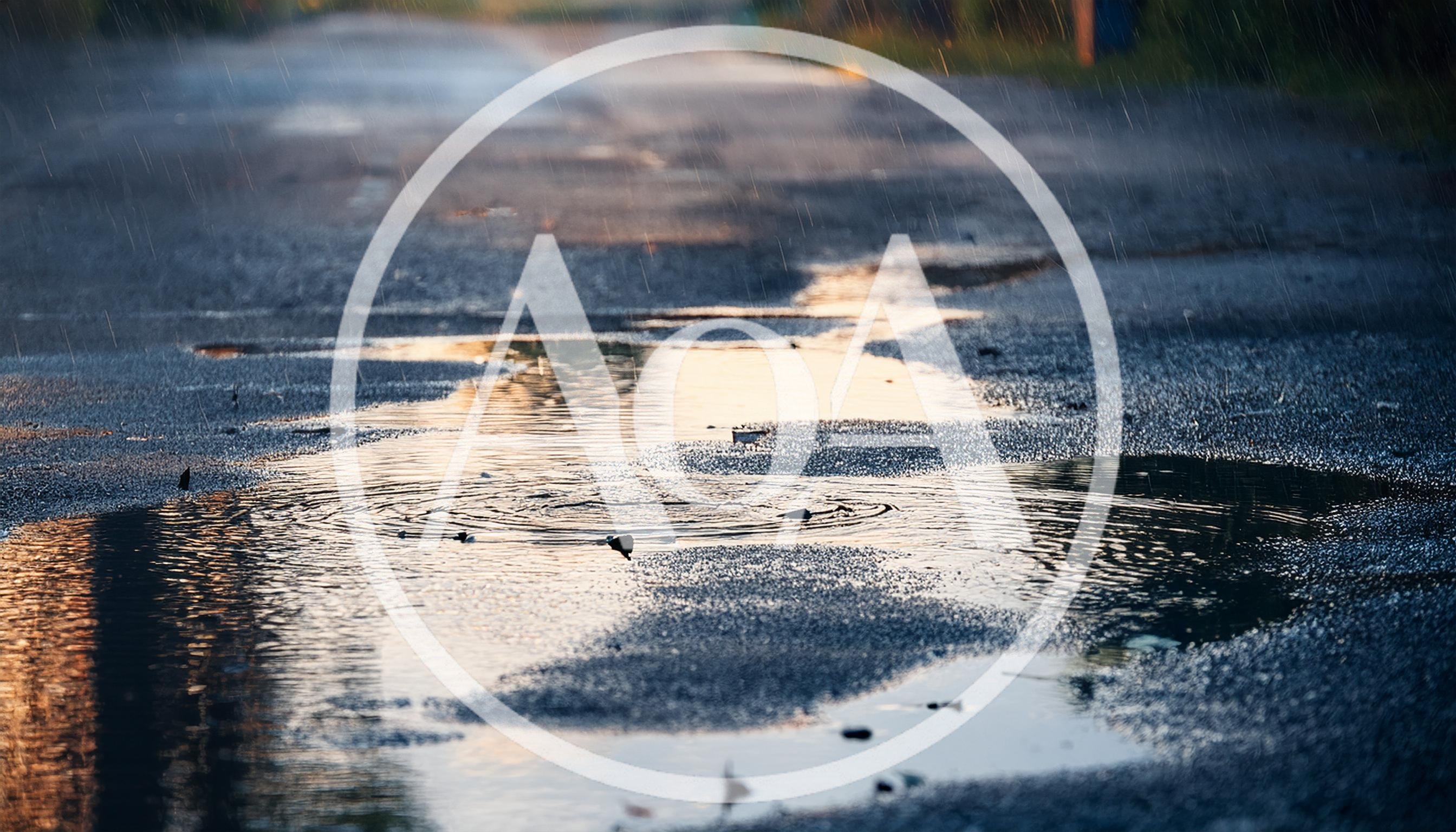 Rain Falling Into Puddles On Asphalt Road