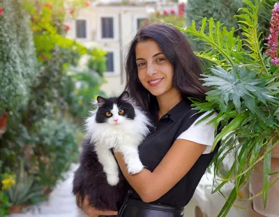 Young Woman Holding Fluffy Black and White Cat