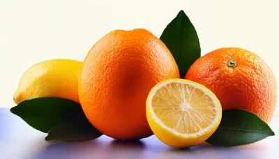 Fresh Citrus Fruits With Green Leaves On White Surface