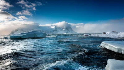 Iceberg Floating In Arctic Ocean Near Snowy Mountains
