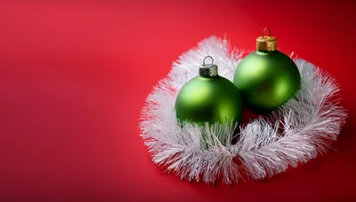 Two Green Christmas Ornaments With White Tinsel