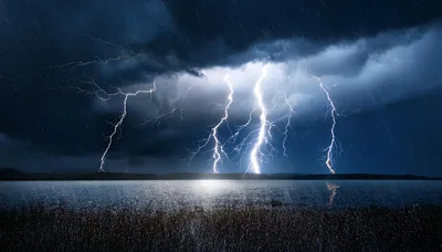 Multiple Lightning Bolts Striking Over A Dark Lake
