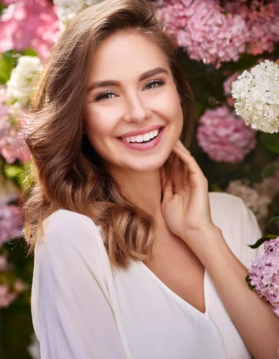 Smiling Woman Posing Amidst Blooming Hydrangea Flowers
