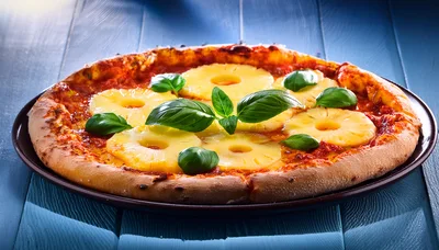 Fresh Pineapple Pizza With Basil Leaves On Blue Wood