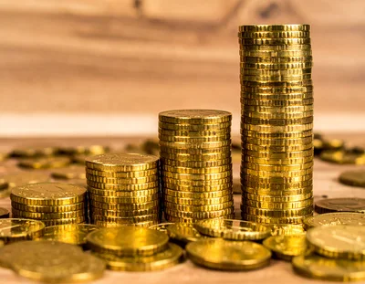 Three Stacks Of Gold Coins On Wooden Surface