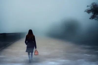 Woman Walking Alone On A Foggy Bridge