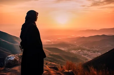 Woman in Hijab Standing on Mountain Overlooking Sunset