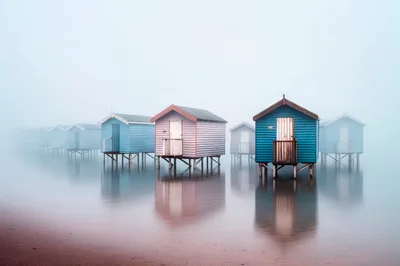 Colorful Beach Huts Standing On Stilts In Thick Fog