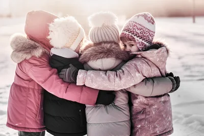 Four Young Children Hugging Together In Snowy Winter