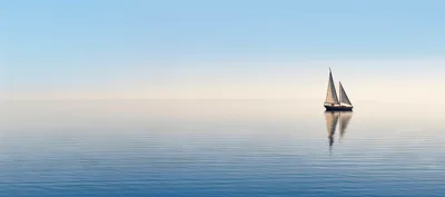 Small Sailboat Floating On Calm Blue Ocean