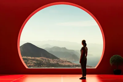 Woman Standing Before A Large Circular Window Overlooking Mountains
