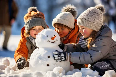 Three Children Building A Snowman Together Outdoors